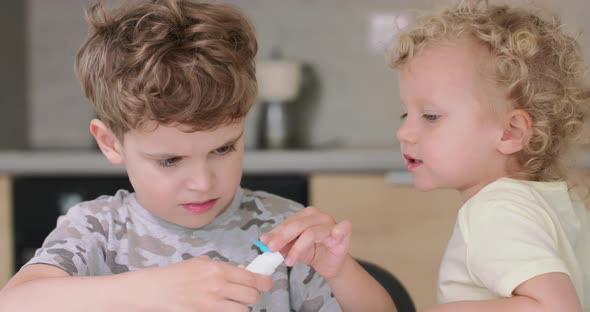 Close Up of Small Boy Who Puts the Glue on the Cutted From Paper Objects During Making Applications