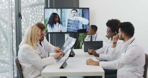Medical Workers Sitting Around Table in Office Room and Having Online Video Conference
