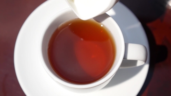 Close Up Of Pouring Milk Into a Cup Of Tea. Slow