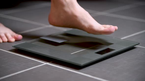 Man steps on a home scale, checks his weight, and steps back off.