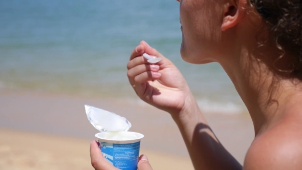 Cute Attractive Woman Eating Yoghurt On The Beach