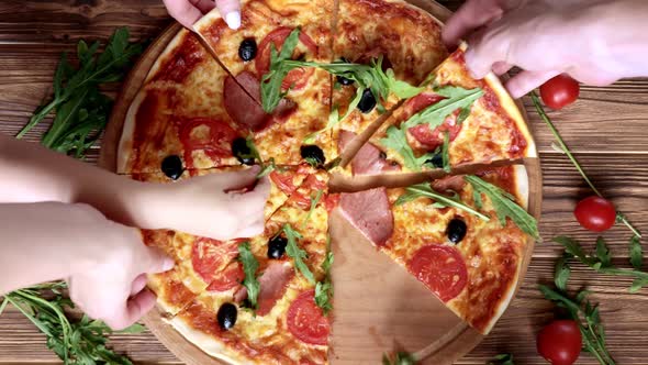 People Hands Taking the Slices Of Pizza. Pizza and Hands close up over wooden background.