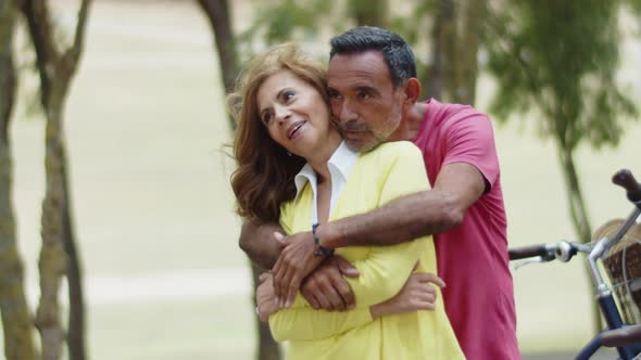 Medium Shot of Bearded Man Hugging and Kissing His Wife in Park