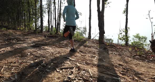 Fitness woman trail runner running on sunrise tropical forest mountain peak,slow motion