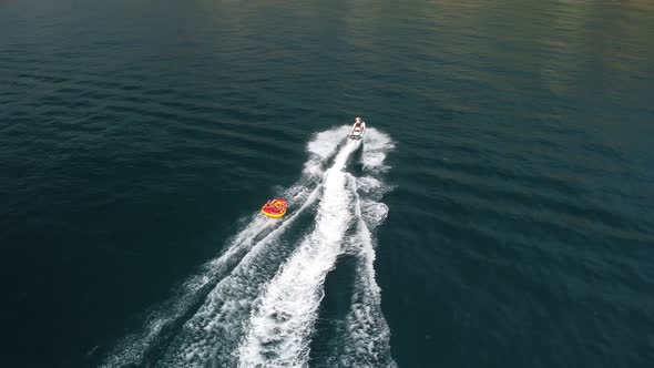 Happy People are Going to Swim on an Air Mattress Behind a Jet Ski