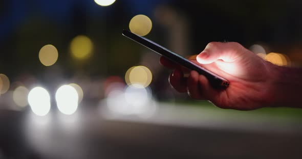 Male Hand Using Mobile Phone in a Night City