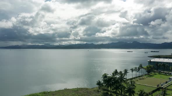 Aerial forward over coastal area of Suva, largest city in Fiji, dramatic clouds