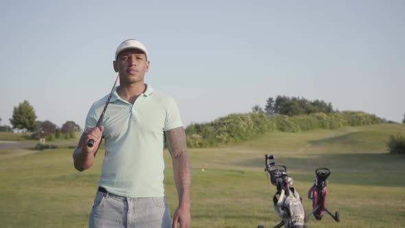 Portrait of a Smiling Confident Successful Middle Eastern Man with a Golf Club Standing on a Golf