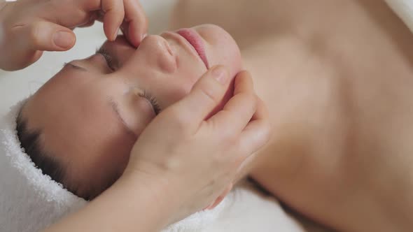 Cute Brunette Woman on Face Massage in Spa Salon