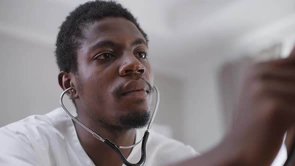 Closeup Focused African American Doctor Auscultating Heart with Stethoscope in Hospital