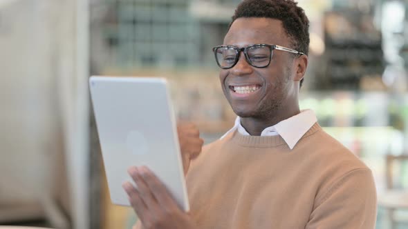 Successful Creative African Man Celebrating on Tablet in Cafe