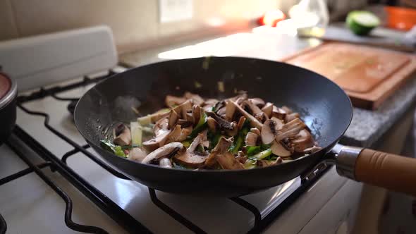 Sliced Mushrooms Falling Into The Pan With Green Squash And Parsley Cooking In The Kitchen. close up