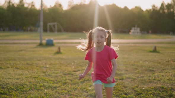 Funny Blonde Girl with Tongue Out Runs Along Playground