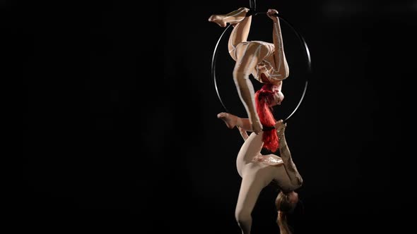 Wide Shot Two Flexible Women Hanging on Air Hoop Spinning at Black Background Performing Tricks