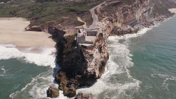 Aerial high angle view of clifftop Fortress of Saint Michael the Archangel and Nazare lighthouse.