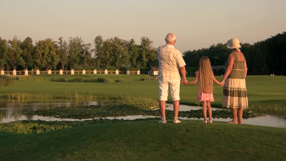 Grandparents with Granddaughter Walking Near Water.