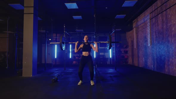 Female Powerlifter is Training in Gym Alone in Night Lifting Heavy Barbell Tensing Muscles of Arms