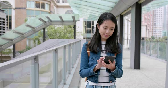 Woman use of smart phone and walking in the street