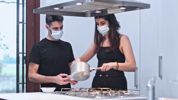 Young couple in protective face mask prepare food in the kitchen Coronavirus prevention concept.