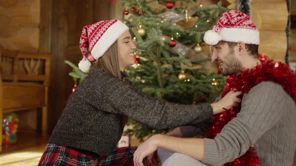 Woman putting a Christmas garland over man's neck