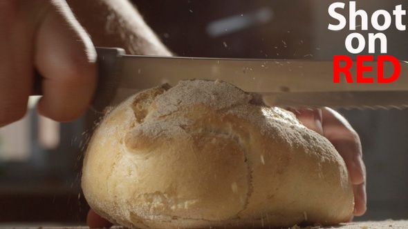 Man Cutting A Piece Of Bread With A Knife In The Kitchen On A Sunny Day Shot On Red Camera