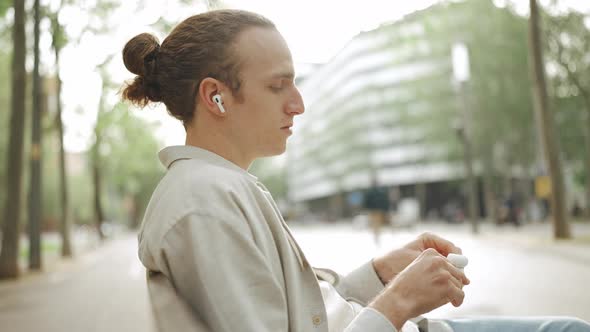 Pretty curly-haired man putting on headphones