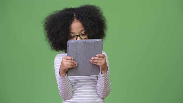 Young Cute African Girl with Afro Hair Using Digital Tablet