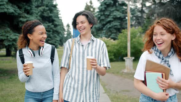 Joyful Youth Laughing Having Fun Walking Outdoors with Books and To Go Coffee