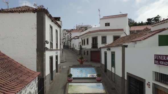 Quaint small street of Firgas with traditional white buildings, Canary Islands. Aerial dolly out