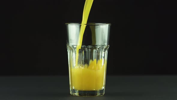 Juice Pouring Into Faceted Glass Isolated on Black Background