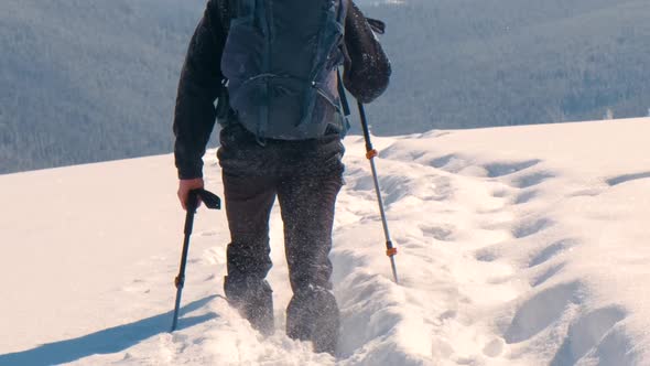 Man Backpacker Hiking Snowy Mountain Hillside on Cold Winter Day