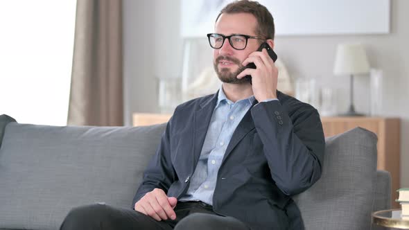 Cheerful Young Businessman Talking on Smartphone at Home 