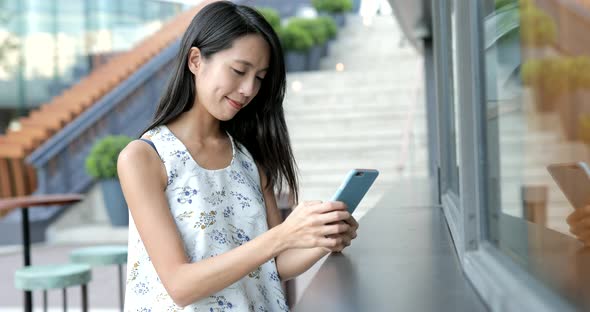 Woman using smart phone at outdoor cafe in the city