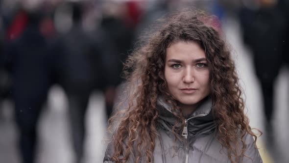 A Young Woman with Curly Hair Poses on a City Street Wearing a Jacket Cold Season