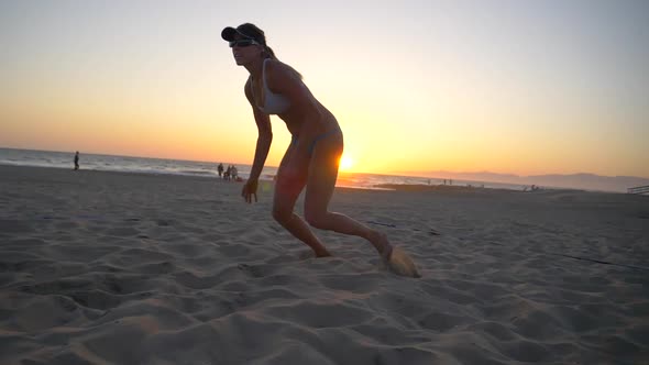 Women players play beach volleyball and a player digs the ball.