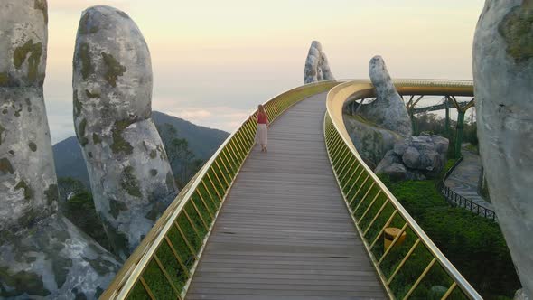 Slowmotion Aerial Shot of a Young Woman Walking on the Golden Bridge in the City of Danang