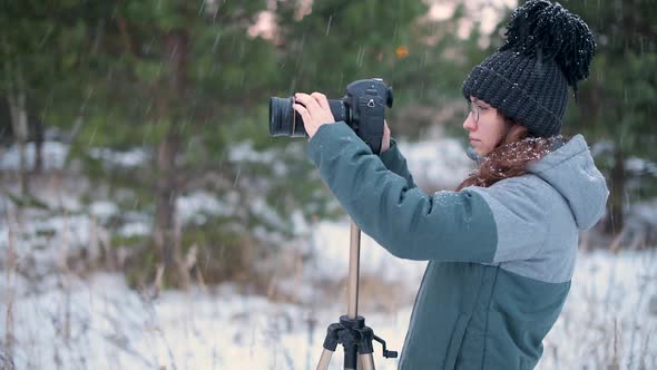 On a snowy day, a girl photographer takes pictures of the winter forest