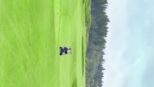 Vertical Shot of Golf Card Riding Across Green Lawn