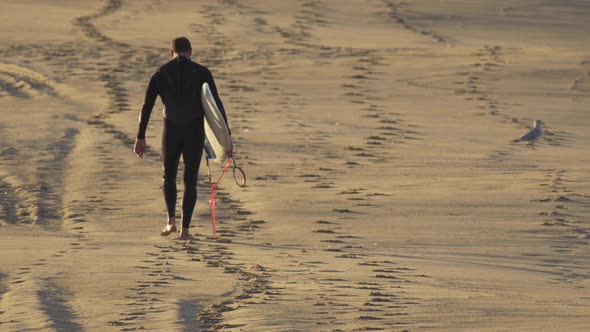 A surfer walking with his surfboard