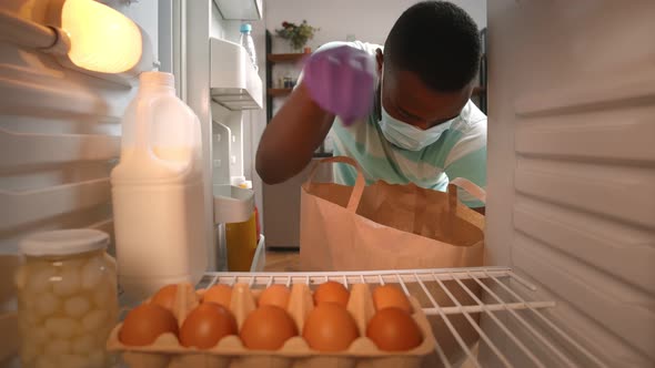 Afro-american Man Unpacking Groceries Bag in Fridge