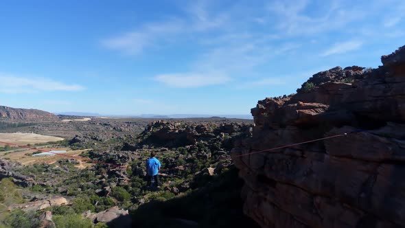 Male highliner sitting on a rope over rocky mountains 4k