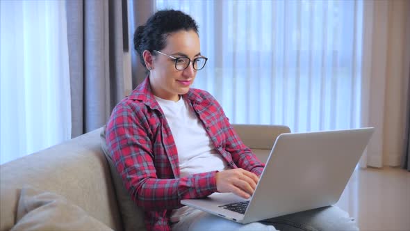 Woman Working on Laptop, Sitting on Sofa at Home, Businesswoman Sits at Home Works Remotely on