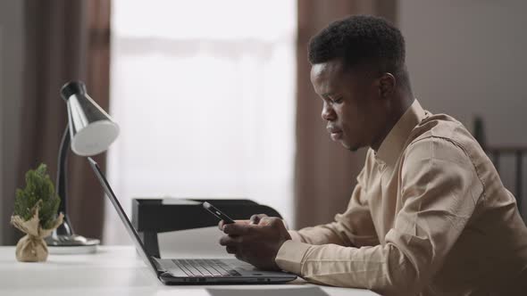 Young Student is Learning Online at Home Sitting at Table with Laptop and Surfing Internet