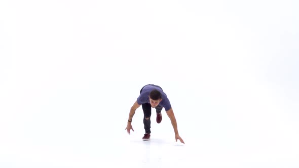 Man Is Dancing Breakdance on the White Background in Simple Grey T-shirt and Grey Jeans. Slow Motion