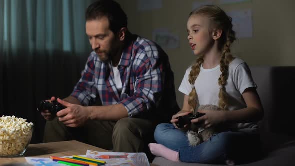 Daughter and Father With Joysticks Playing Video Game Together Home, Having Fun
