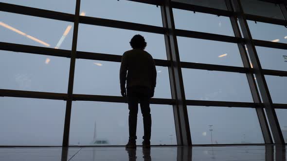 Silhouette of Man Looking Through Window at Airport