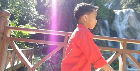 Kid Walking, Waterfall On Background