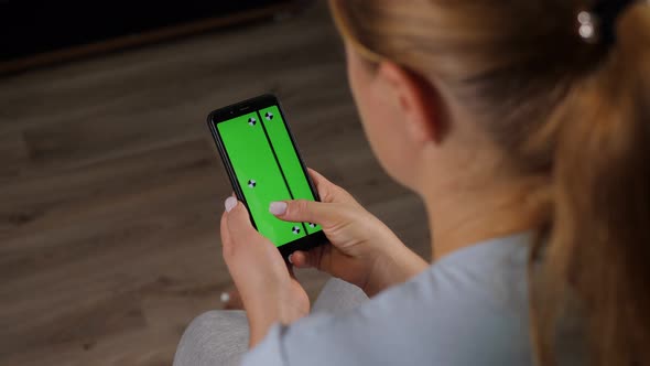 Closeup of a Woman Holding a Phone with a Green Screen While Sitting at Home