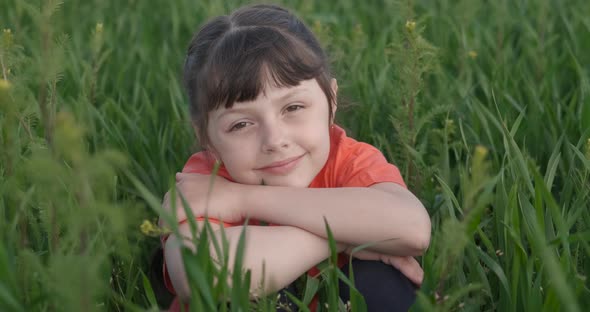 Child Sits in the Green Meadow