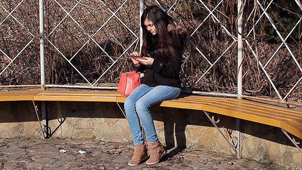 Young Woman Using Tablet on Park Bench